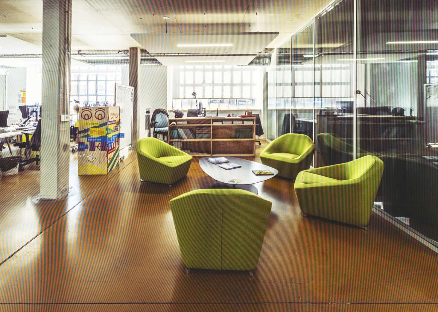 Bureau moderne avec fauteuils verts dans un espace de coworking lumineux et accueillant.